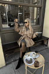 a lady wears a camel wool trench coat with black boots